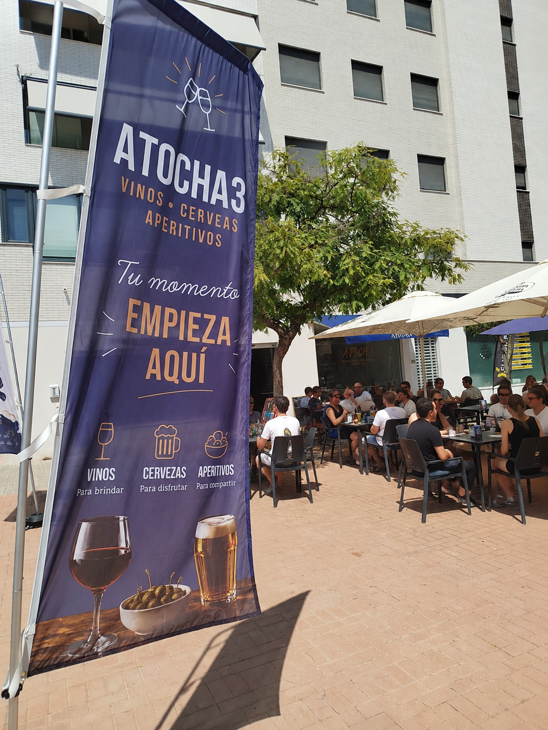 Terraza exterior de Atocha 3 con el banner de la marca y clientes en las mesas
